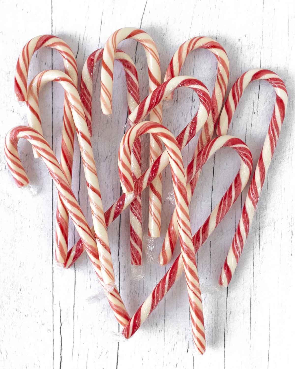 An overhead shot showing candy canes scattered on a white wooden table.