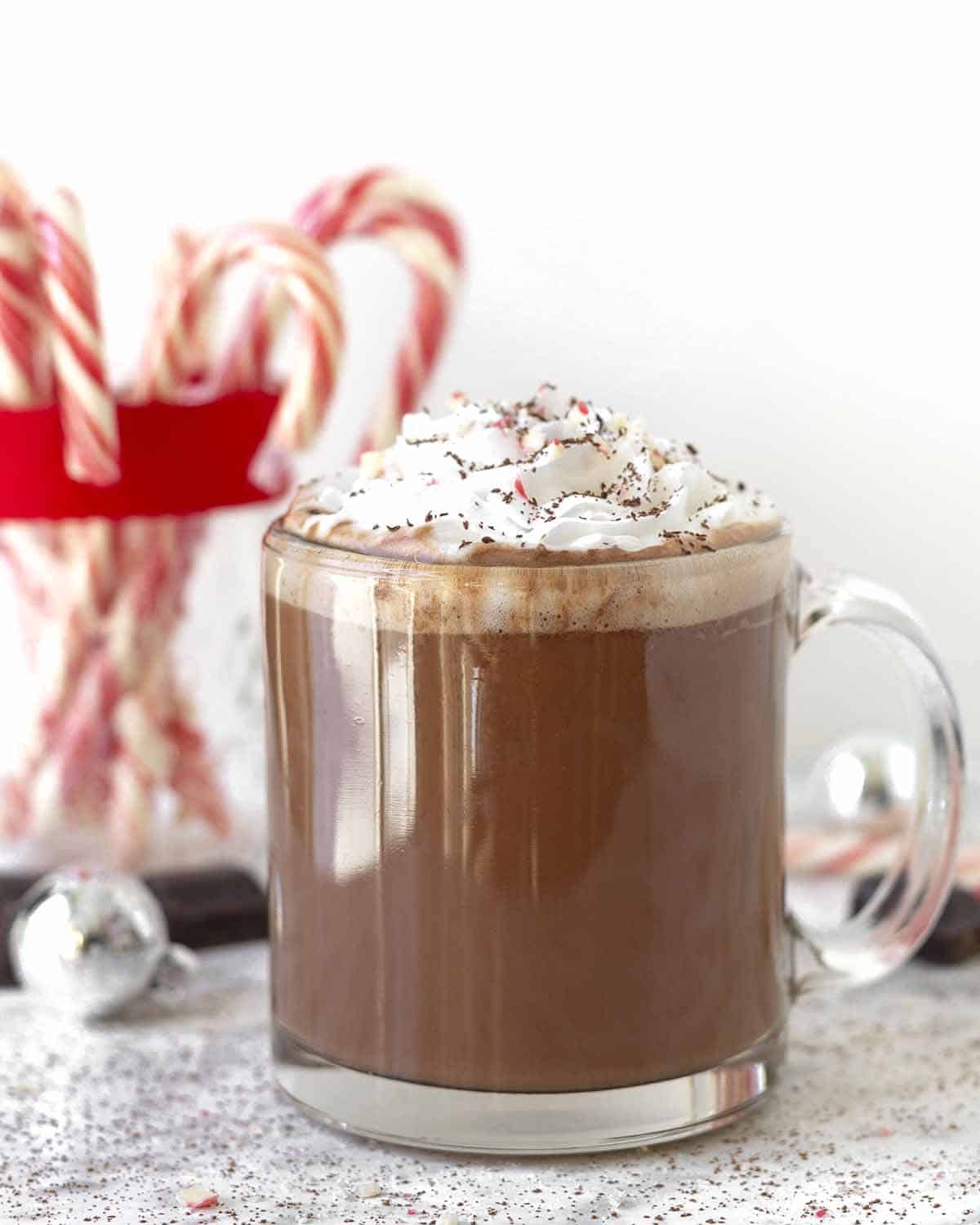 A mug filled with peppermint mocha, the drink is garnished with whipped cream, crushed candy canes and shaved chocolate.