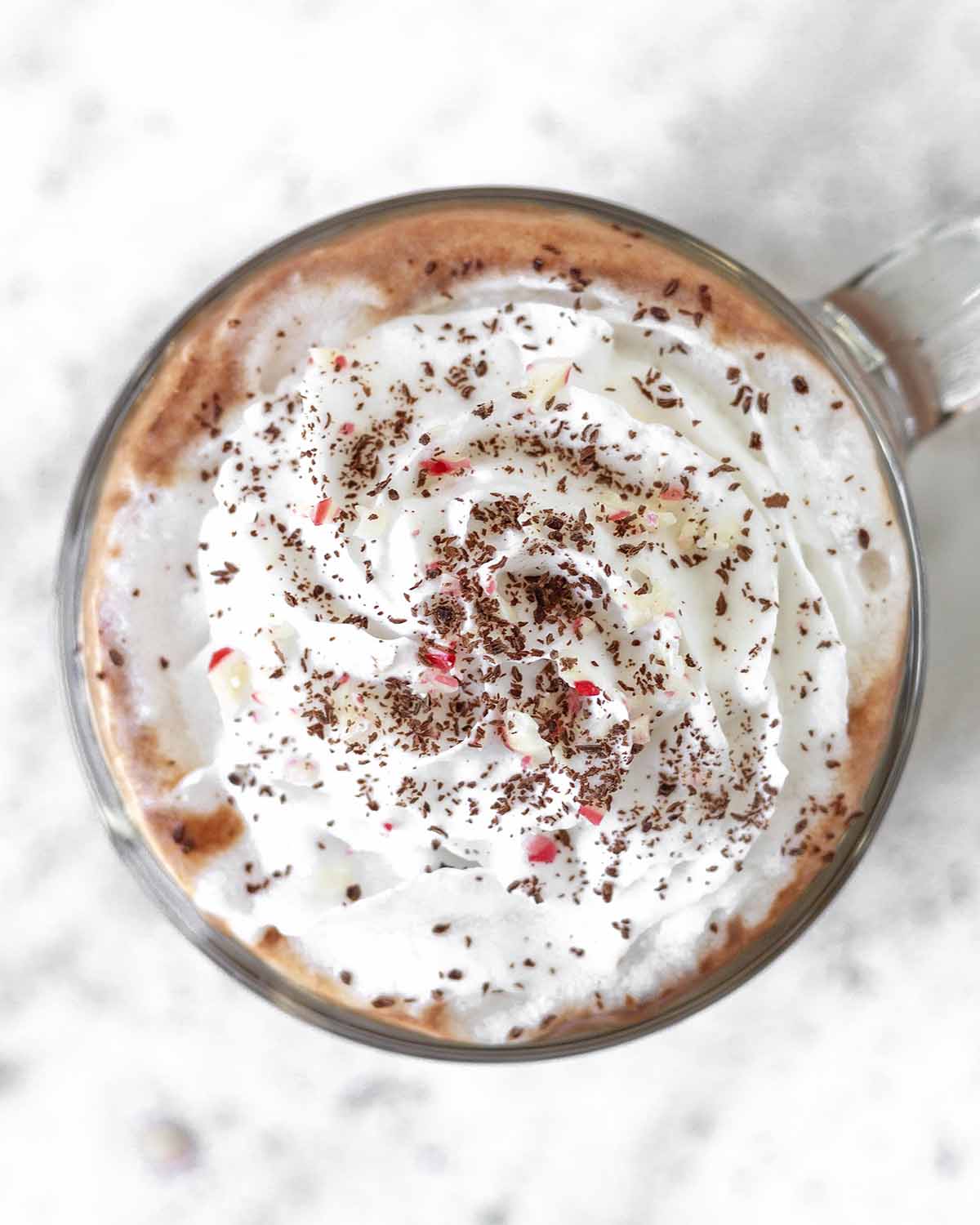 An overhead shot showing the top of a peppermint mocha drink, it’s topped with whipped cream.
