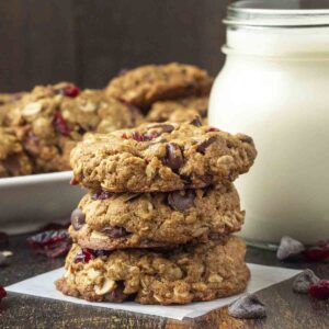 Three vegan oatmeal cranberry chocolate chip cookies stacked on top of each other.