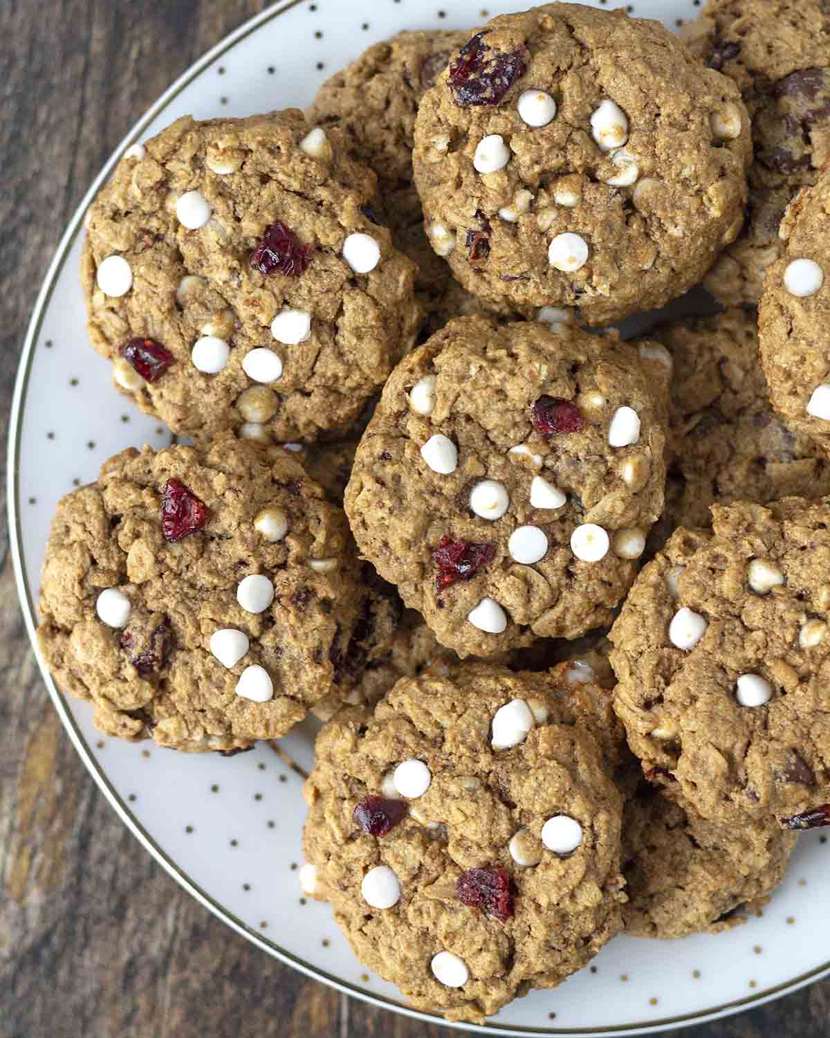 An overhead shot showing a plate of vegan oatmeal cranberry cookies with white chocolate chips.