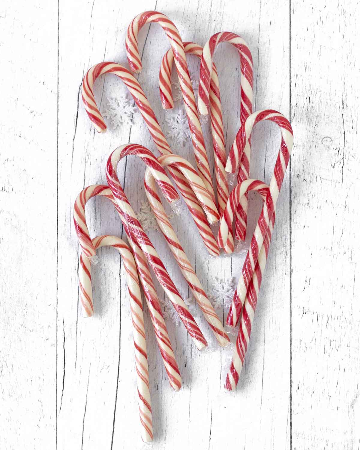 Full size vegan candy canes lying on a white wooden table.