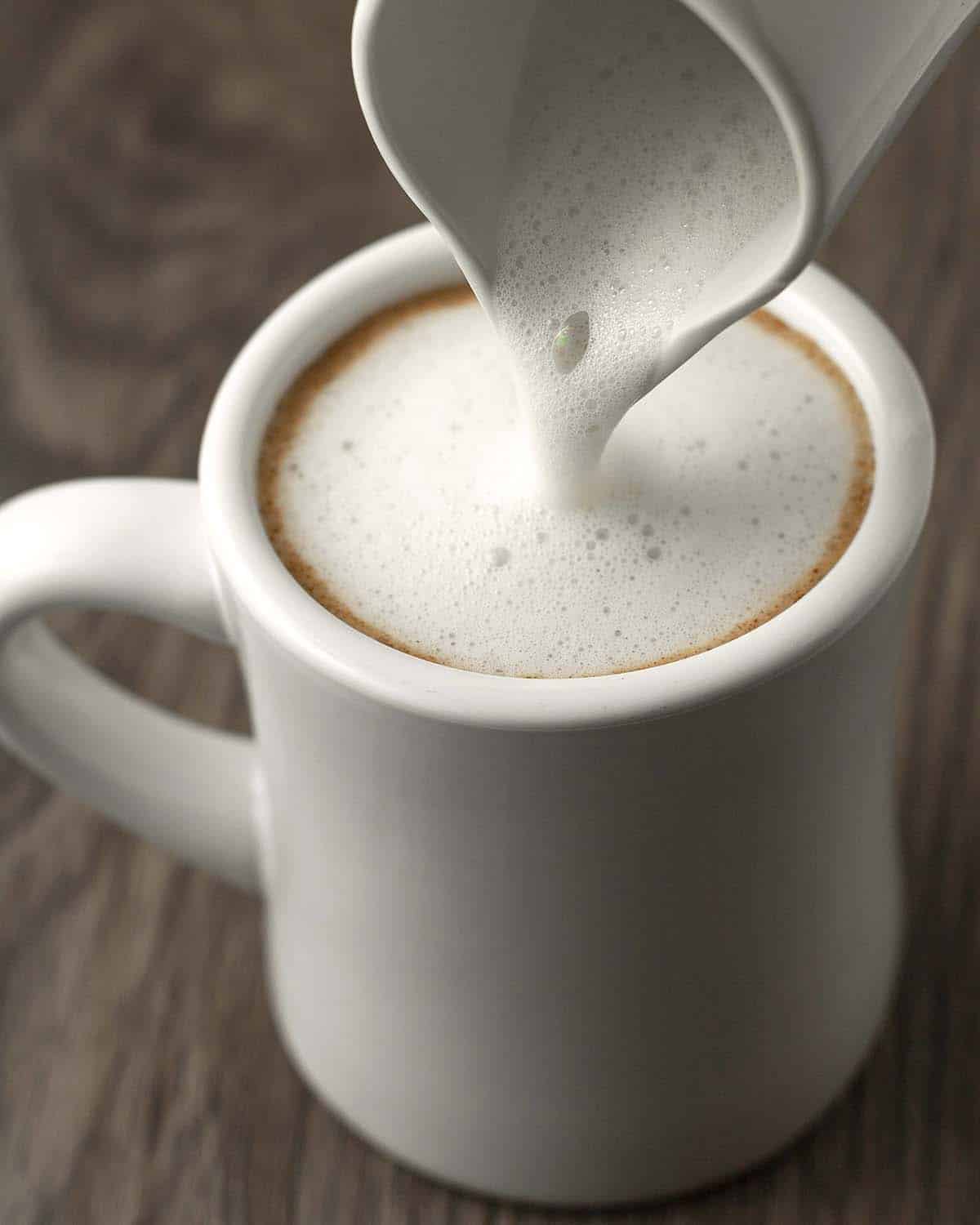 Foamed milk being poured into a mug of gingerbread latte.