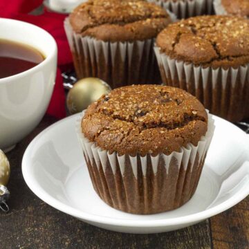 A gingerbread muffin on a small plate, more muffins sit in the background.
