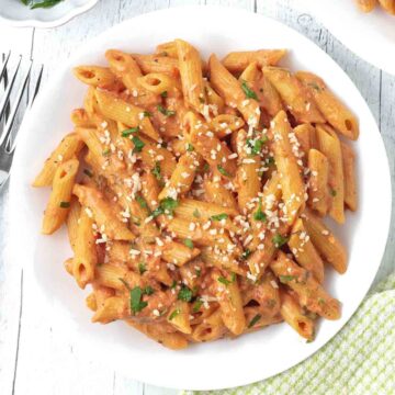 Penne pasta with creamy tomato sauce on a white plate.