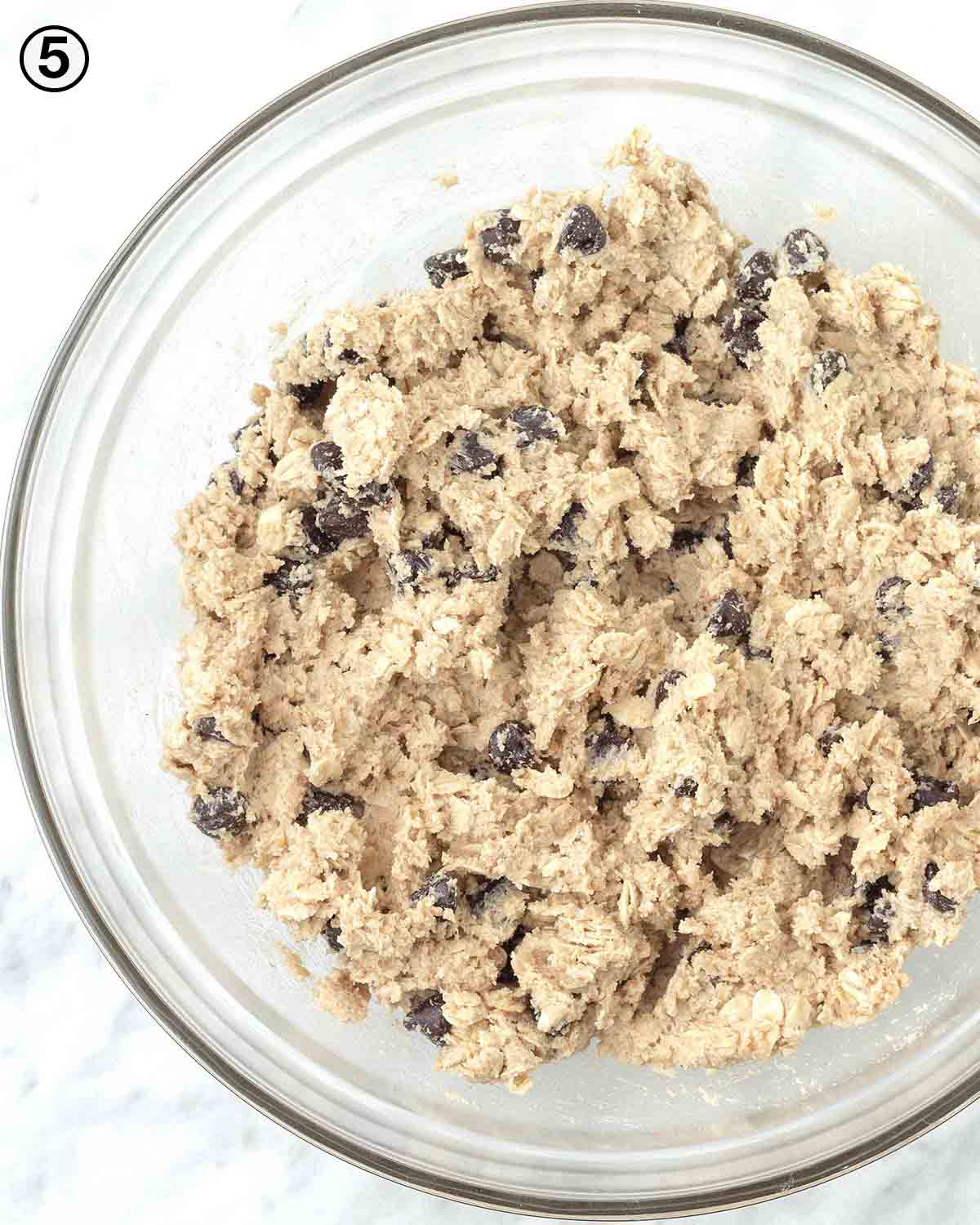 An overhead shot of cookie dough in a glass mixing bowl.