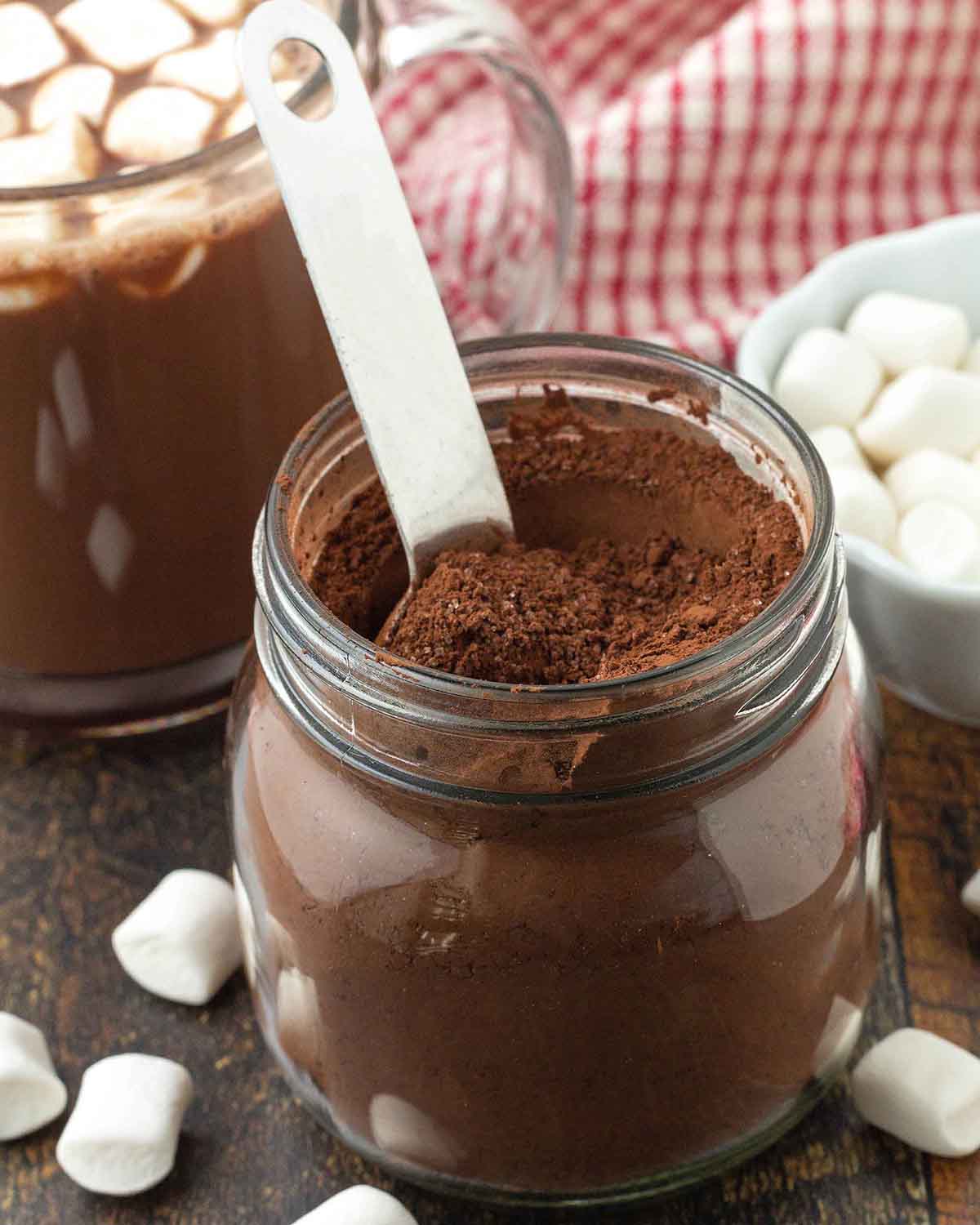 A mason jar filled with hot cocoa mix; a metal tablespoon is also in the jar.