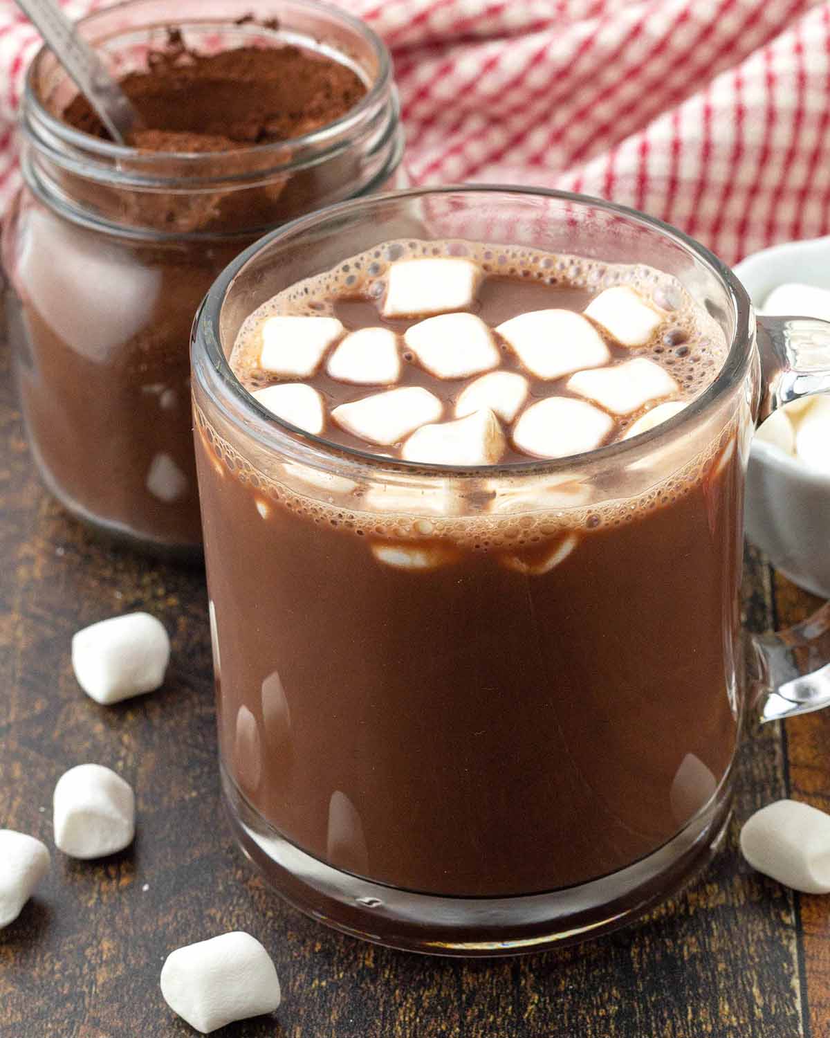 A glass mug filled with hot chocolate topped with marshmallows.