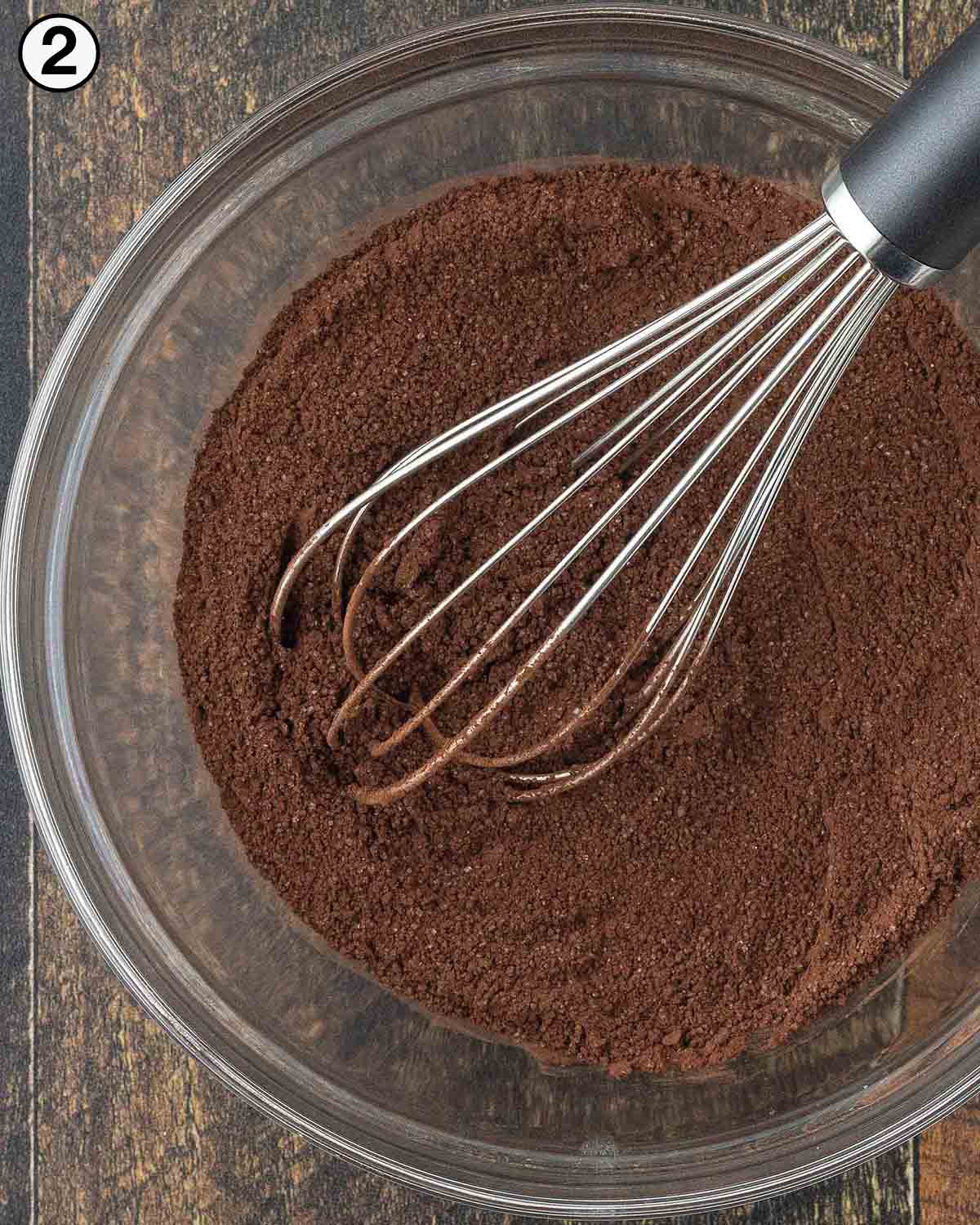 Hot cocoa mix in a glass bowl with a whisk.