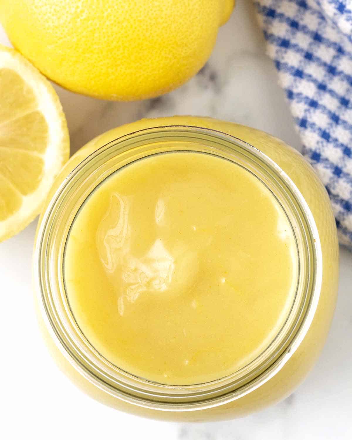 An overhead shot of homemade vegan lemon curd in an opened glass jar.