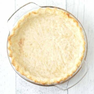 A pie crust that has been blind-baked in a glass pie dish.