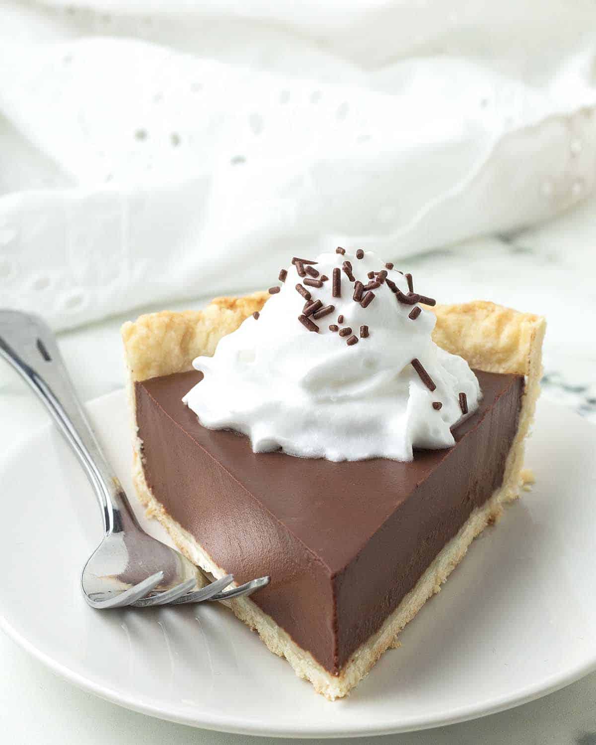 A slice of vegan gluten-free chocolate pie sitting on a plate, a fork sits on the plate beside the slice.