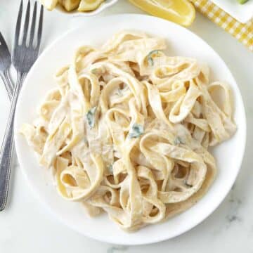 Tagliatelle pasta with creamy tahini sauce on a white plate.