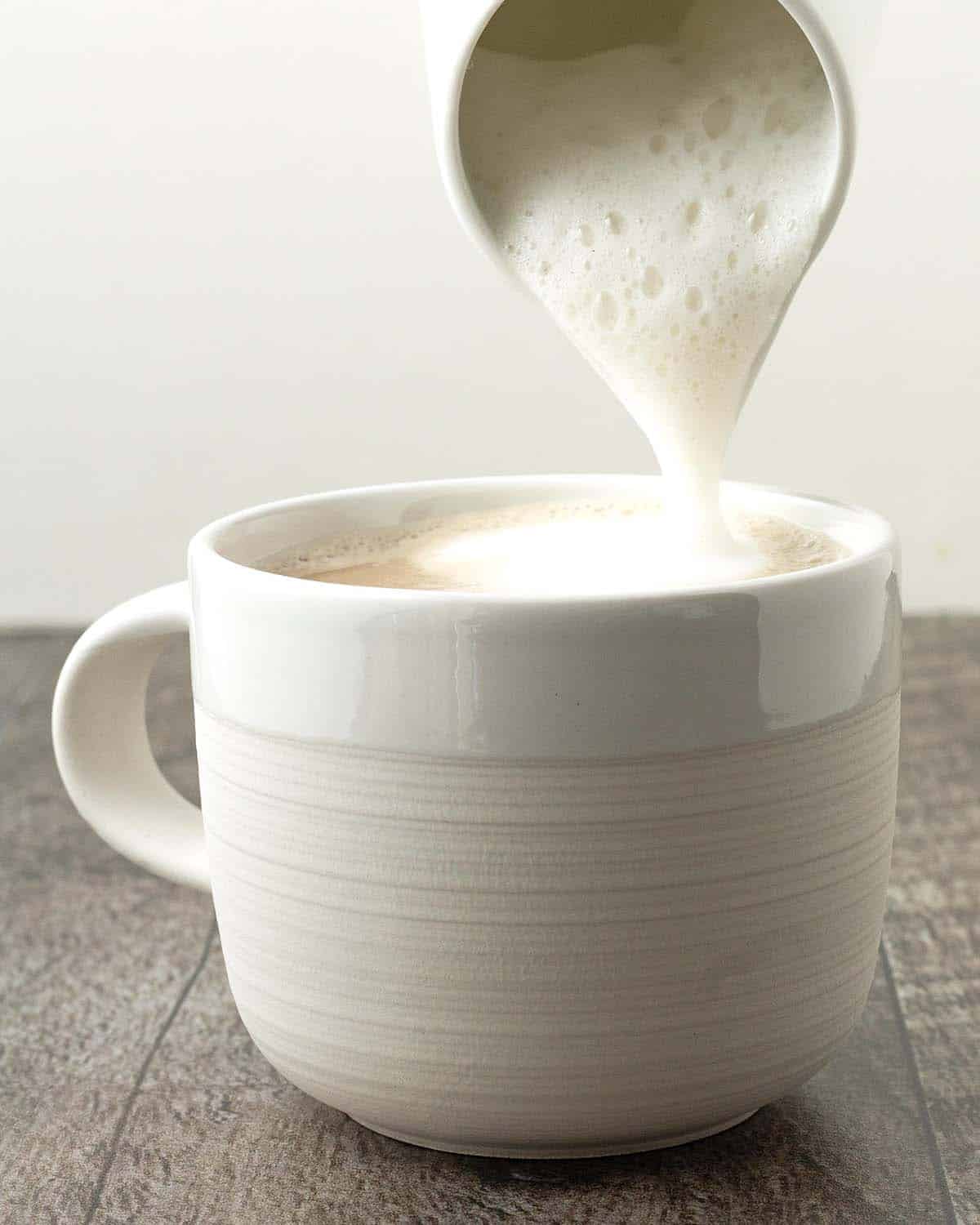 Foamed almond milk being poured on top of a latte.