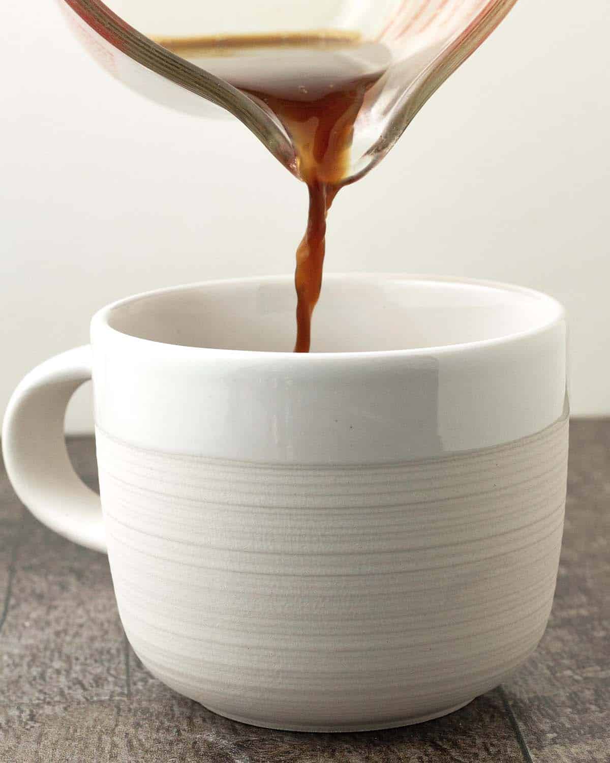 Coffee being poured from a glass container into a mug.