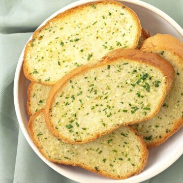 A dish filled with fresh slices of garlic bread.