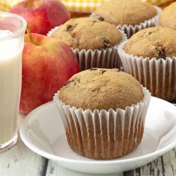 A vegan applesauce muffin on a small plate, more muffins sit in the background.