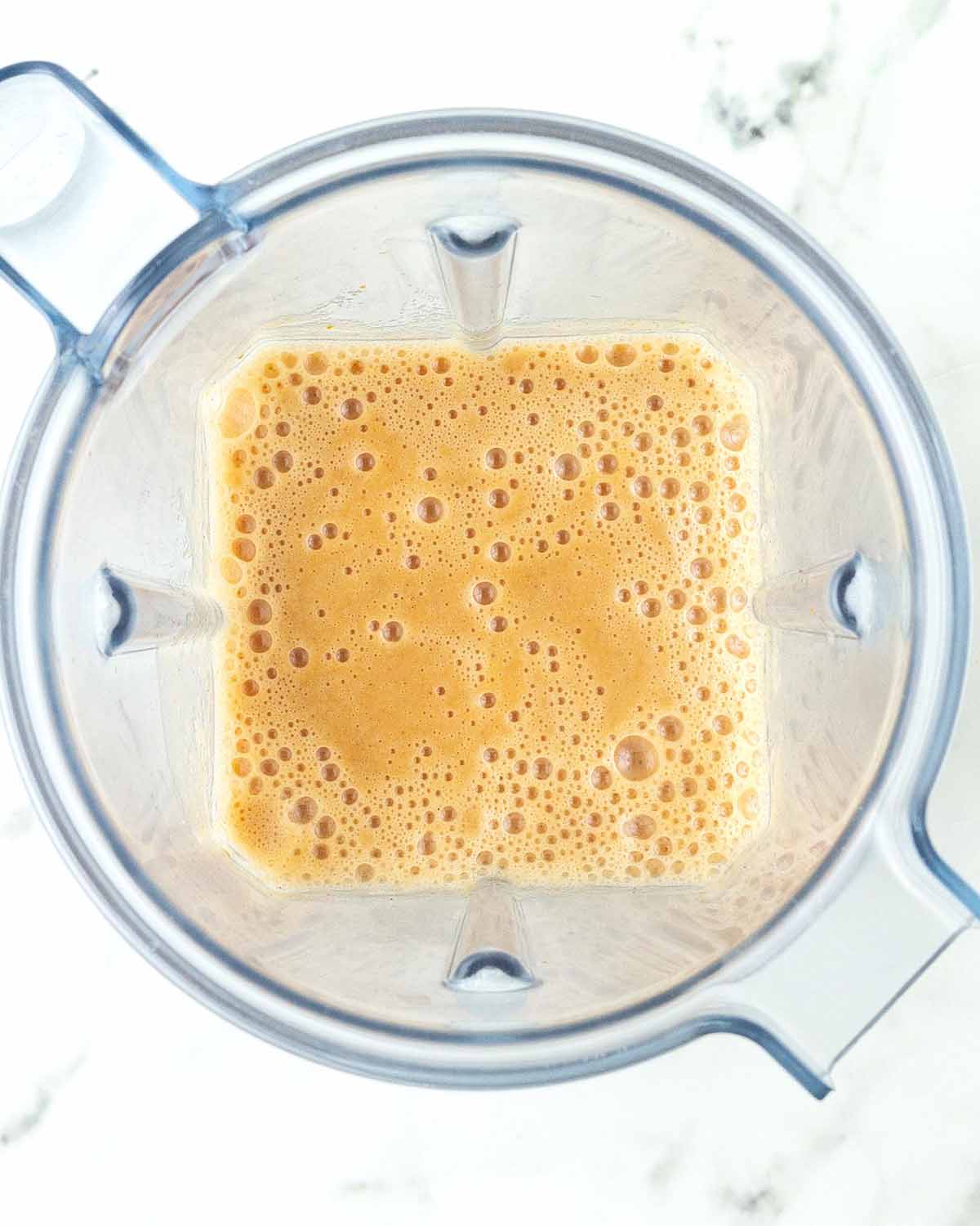 An overhead image of freshly blended pumpkin smoothie in a blender canister.