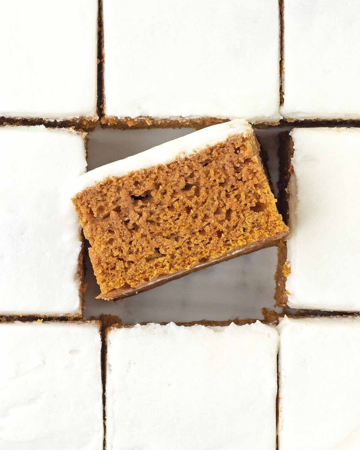 An overhead image of frosted and sliced pumpkin bars, the bar in the middle is turned on its side to show the texture.