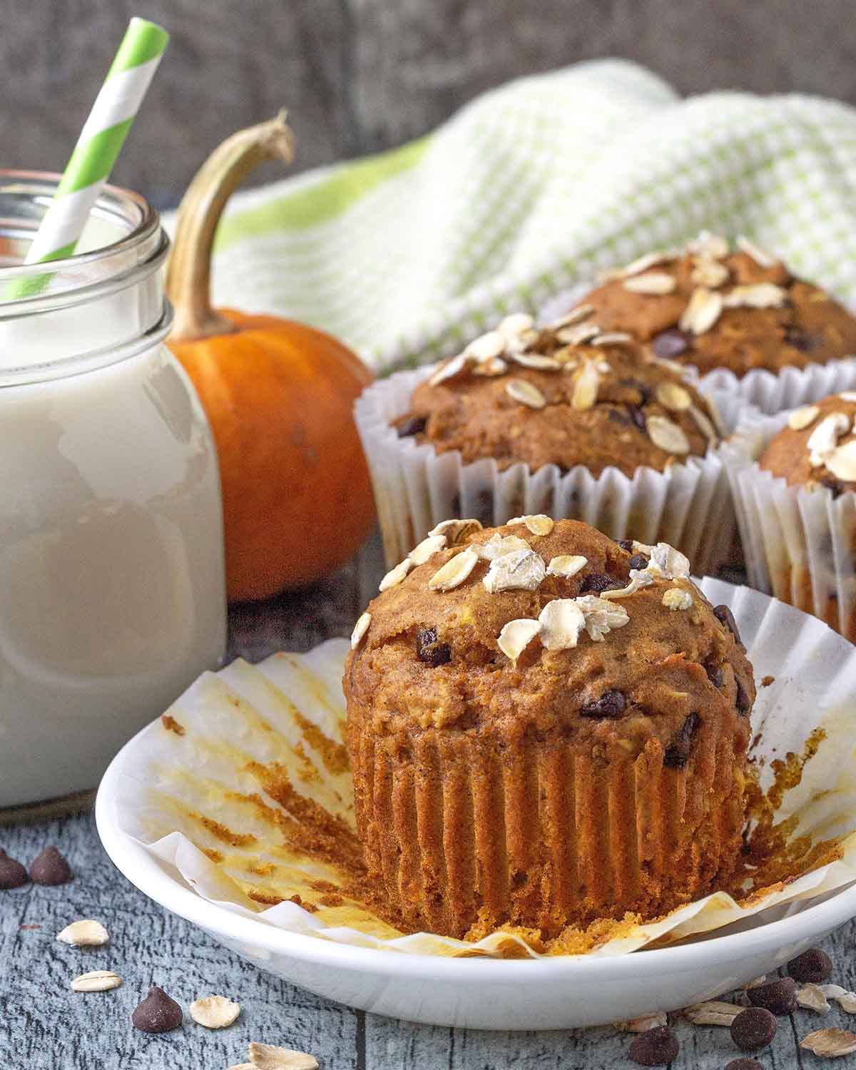A pumpkin oatmeal muffin on a plate, the muffin wrapper has been peeled away.