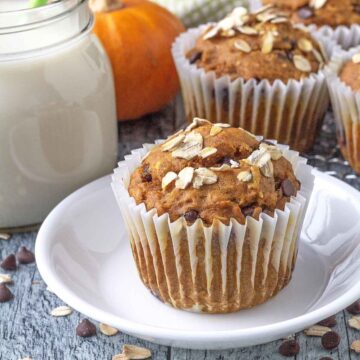 Close up shot of a vegan pumpkin oatmeal muffin on a small white plate.