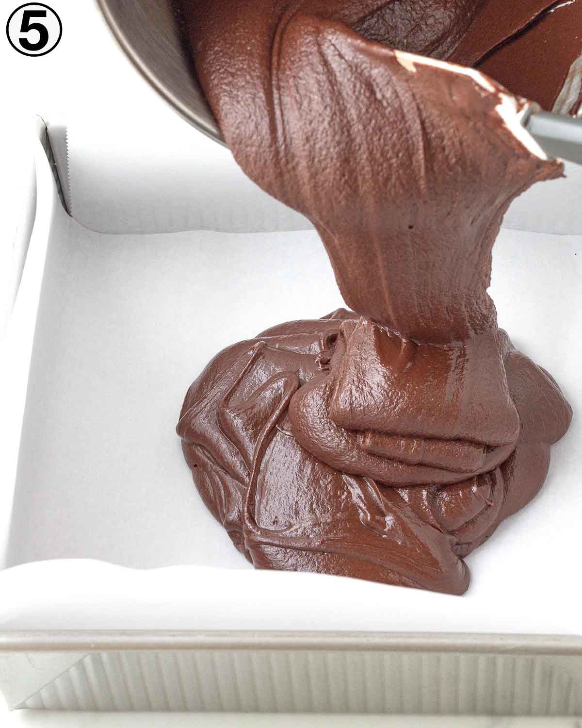 Vegan chocolate fudge being poured into a square pan.