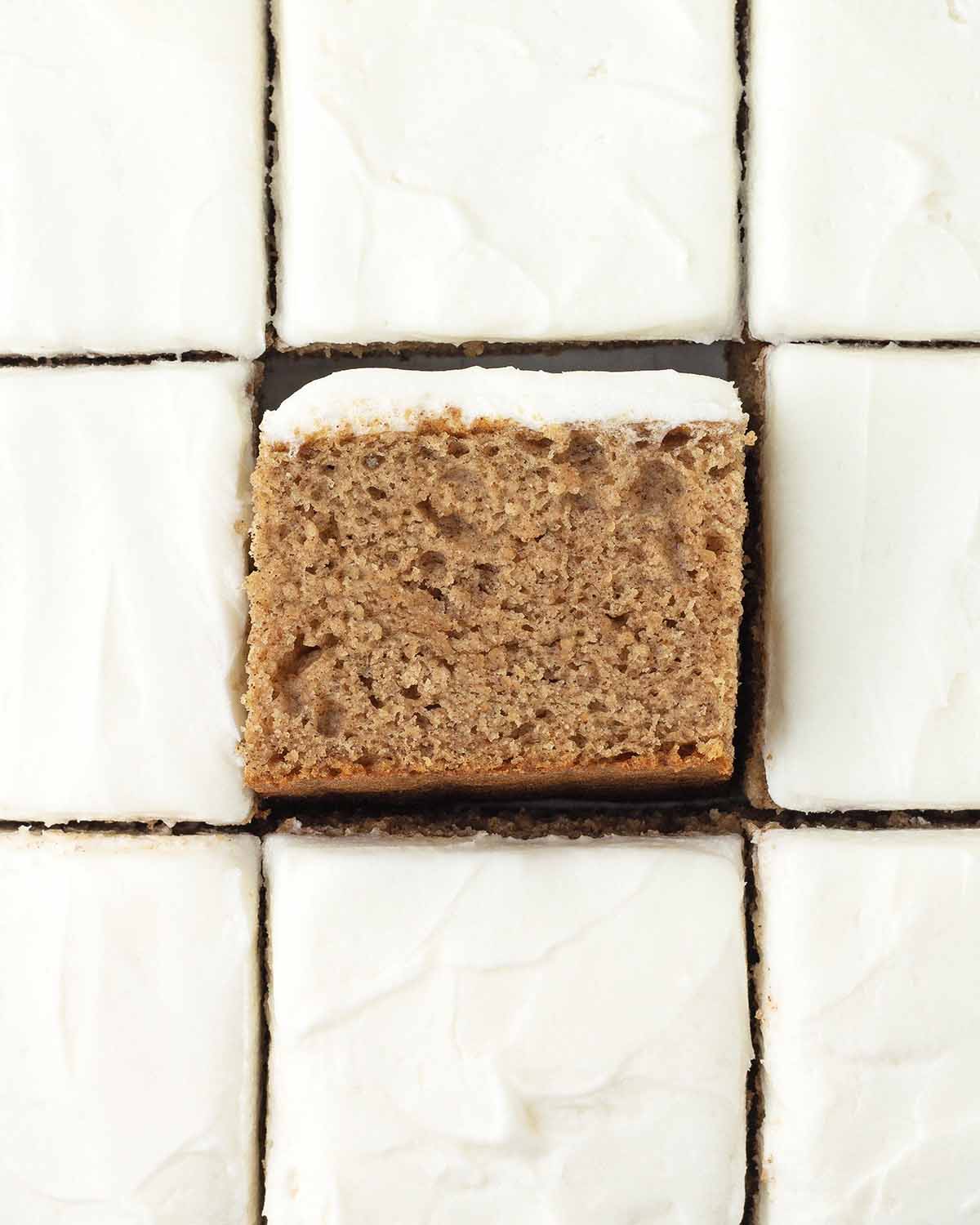 An overhead image of frosted and sliced pumpkin bars, the bar in the middle is turned on its side to show the fluffy texture.