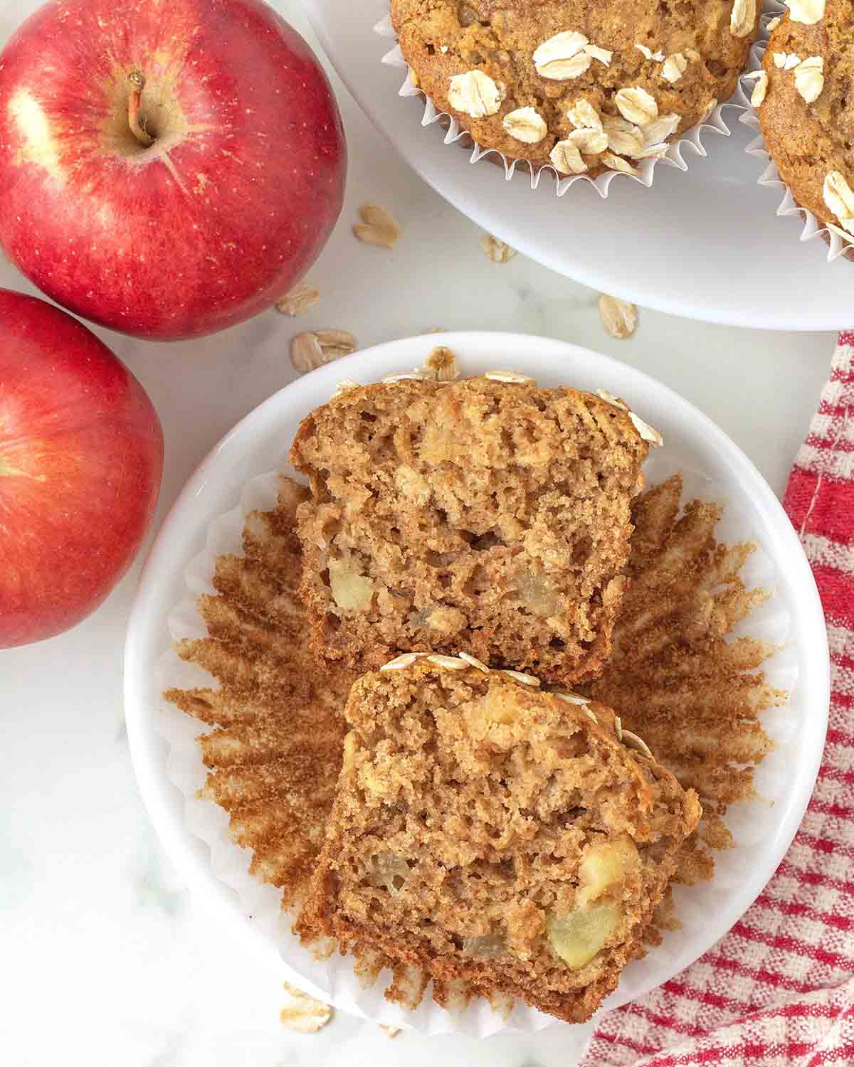 An overhead shot of a vegan apple oat muffin cut in half to show the fluffy inside.