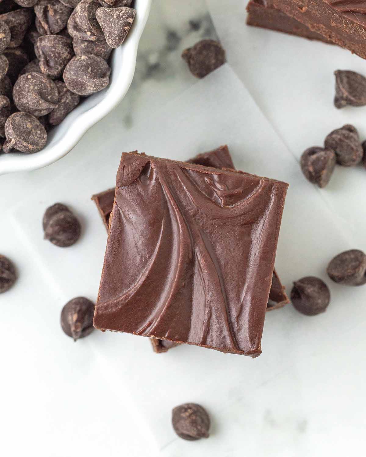 An overhead image showing two pieces of vegan fudge, chocolate chips surround the fudge.