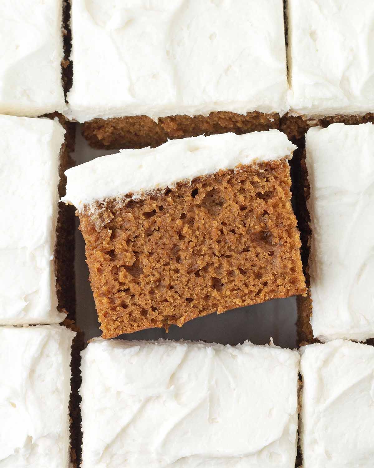 An overhead image of sliced gingerbread cake, the square in the middle is turned on its side to show the fluffy texture.