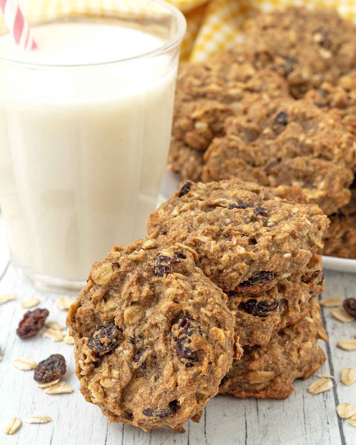 A stack of three oatmeal breakfast cookies, one cookie is leaning against the stack.