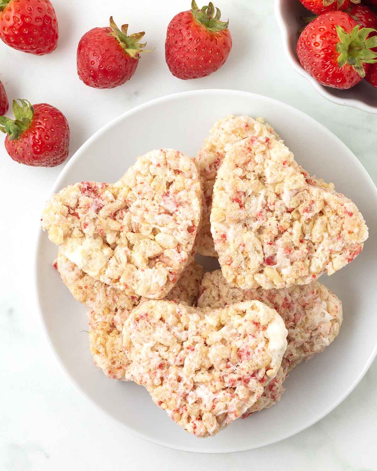 An overhead image of heart-shaped strawberry rice crispy treats on a plate.