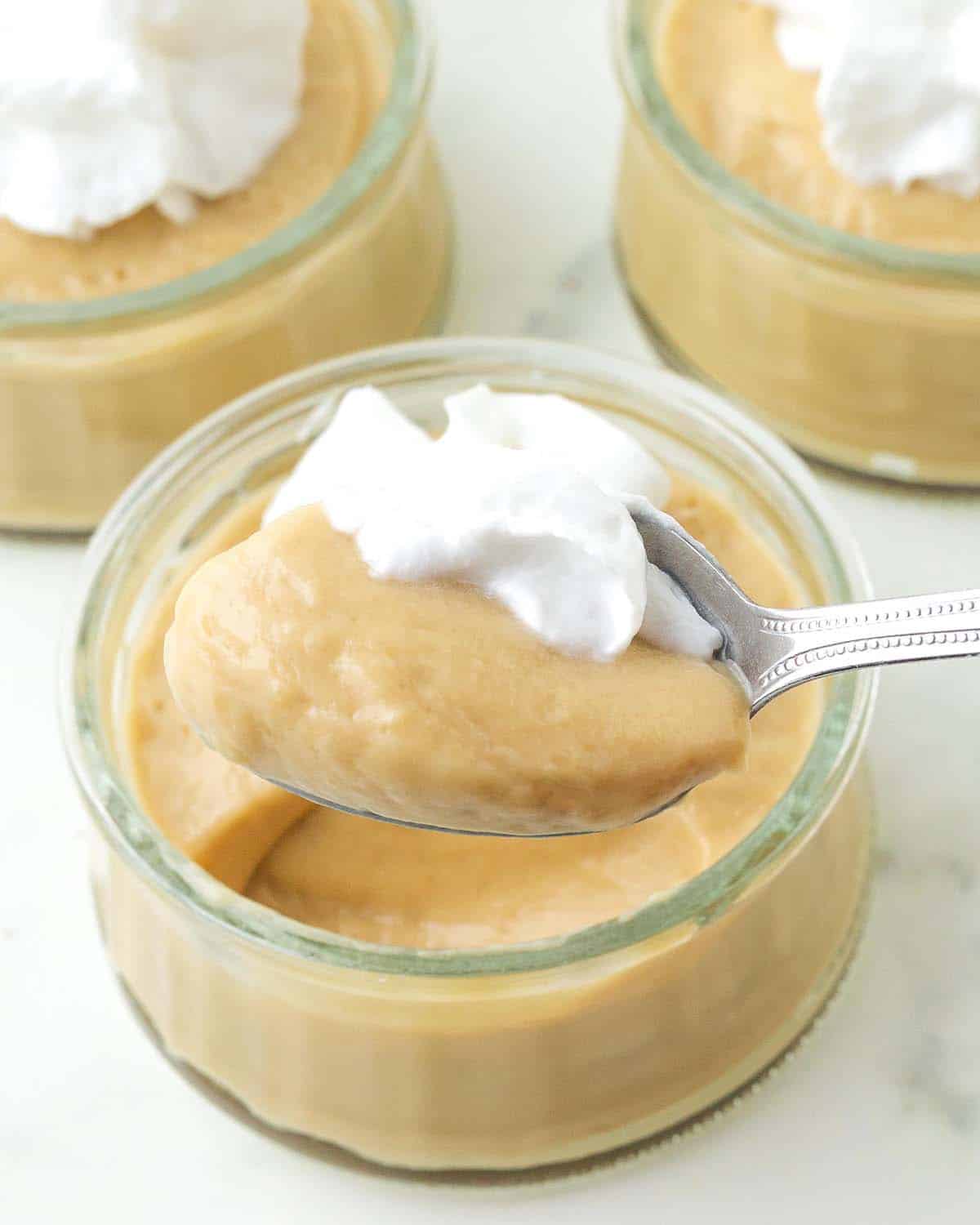 Butterscotch pudding and whipped cream on a spoon.