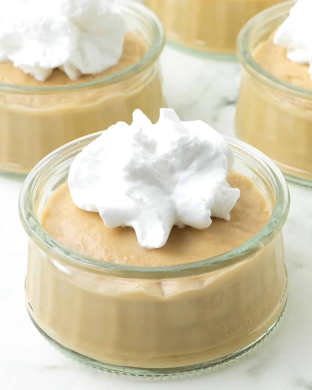 Butterscotch pudding in a glass bowl topped with whipped cream.
