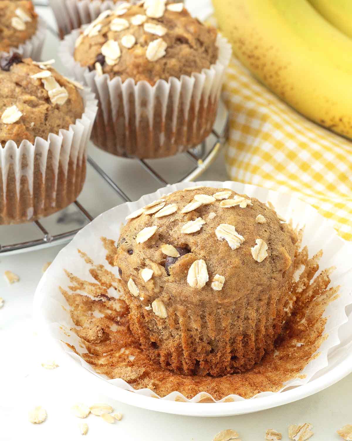 A banana oat muffin on a plate, the muffin wrapper has been peeled away.