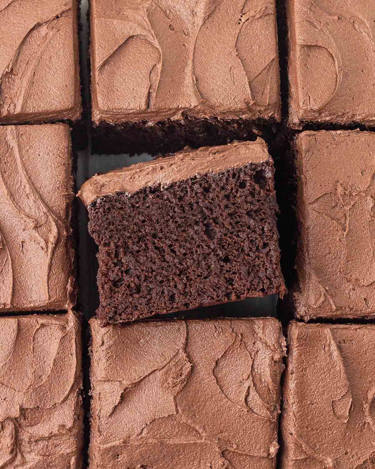 An overhead image of sliced chocolate banana cake, the square in the middle is turned on its side to show the fluffy texture.