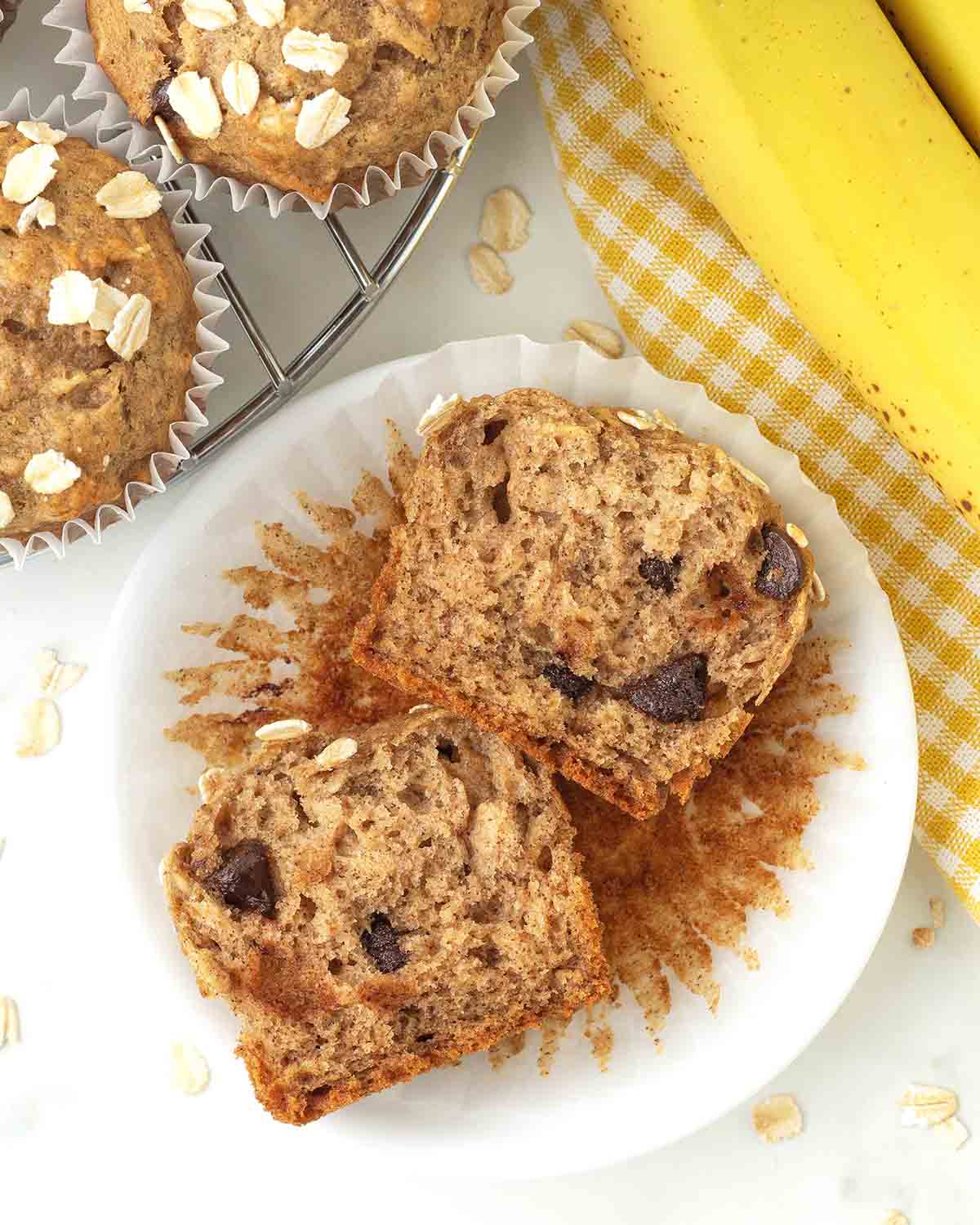An overhead shot of a vegan gluten-free banana oatmeal muffin cut in half to show the fluffy inside.