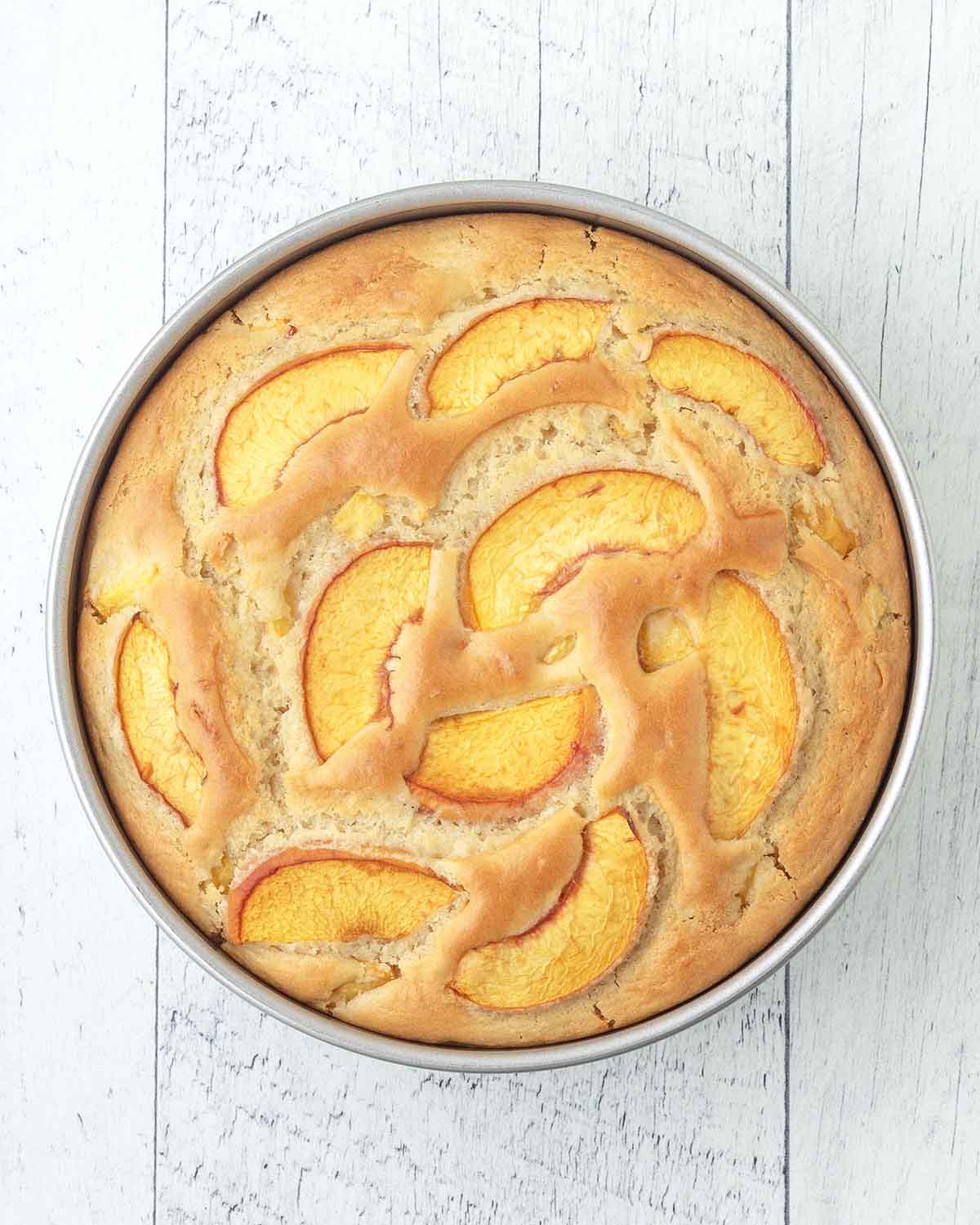 A freshly baked peach cake in a cake pan.