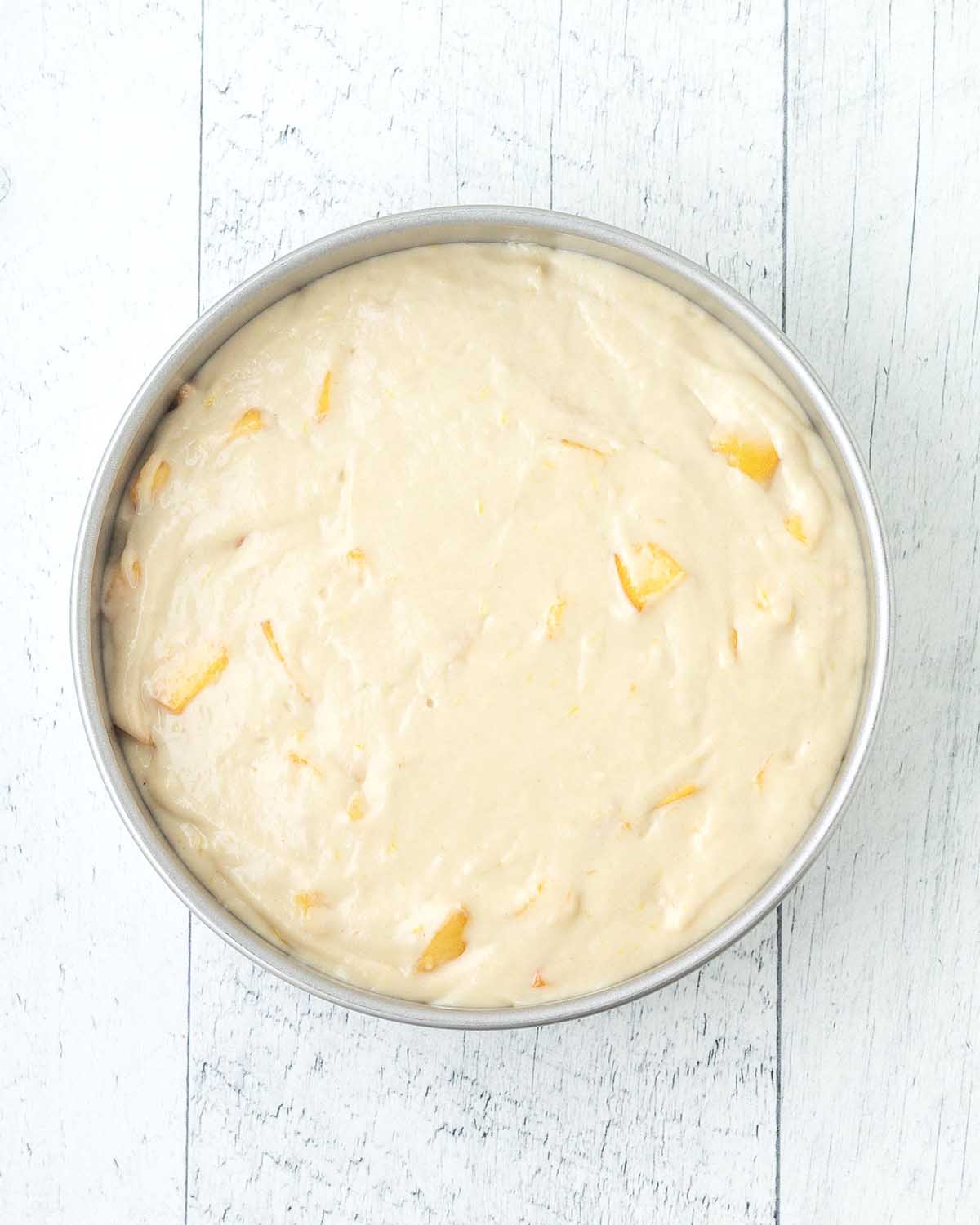 Unbaked peach cake batter in a cake pan.