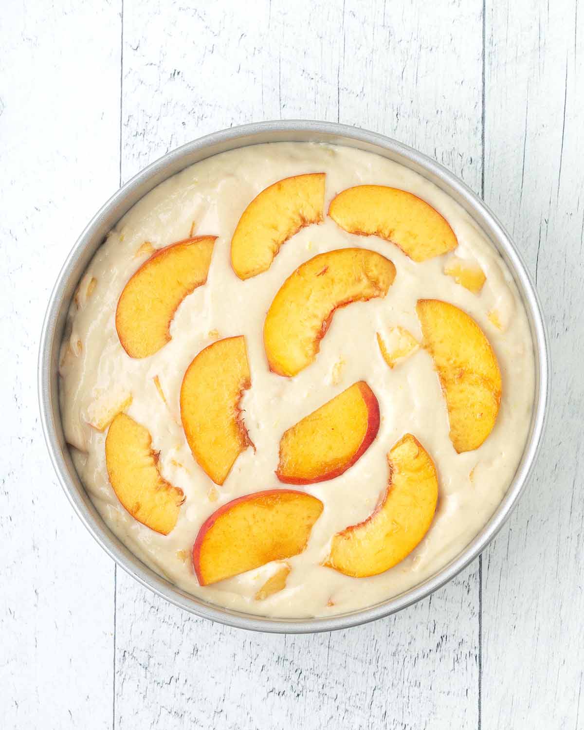 Unbaked peach cake batter in a cake pan.