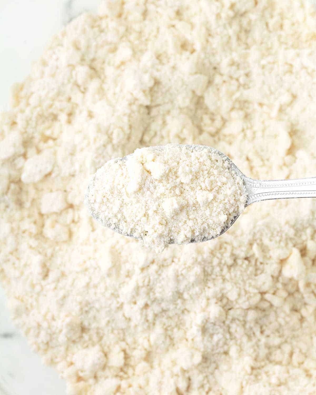 A spoon full of flour that has had butter cut into it to make scones.