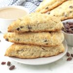 Three vegan coconut raisin scones stacked on a white plate.