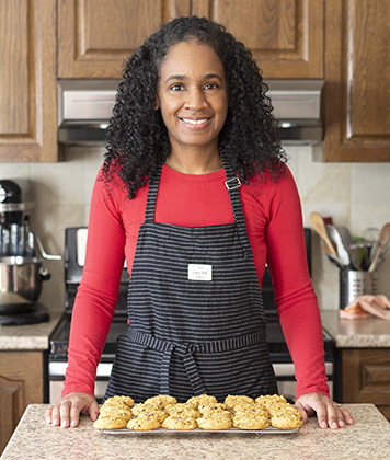 A person standing in front of a tray of cookies.