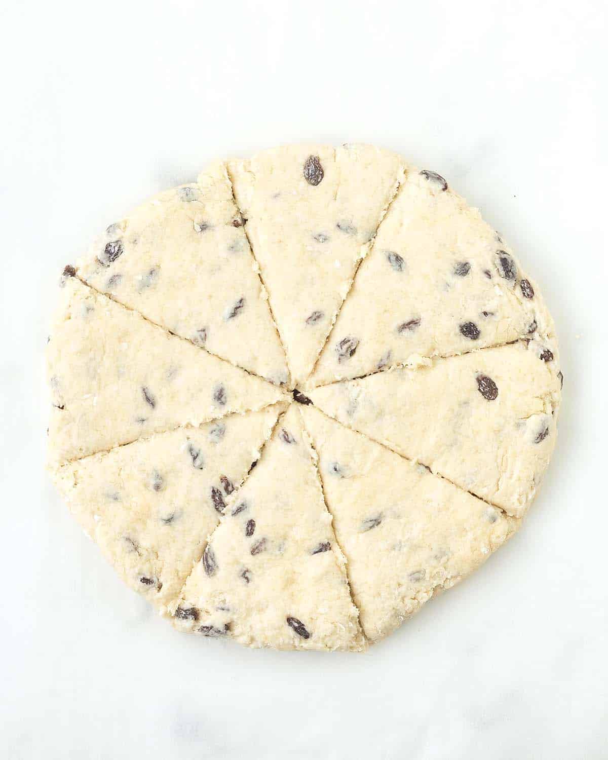 A round disc of scone dough that has been cut into eight wedges.