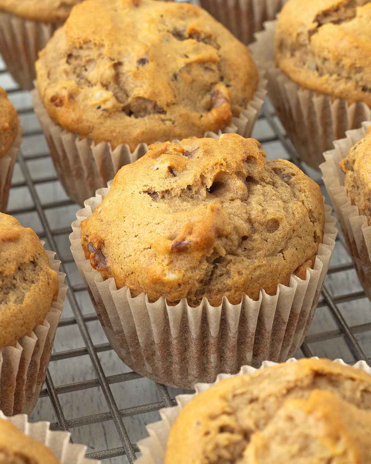 Freshly baked vegan banana muffins cooling on a metal rack.