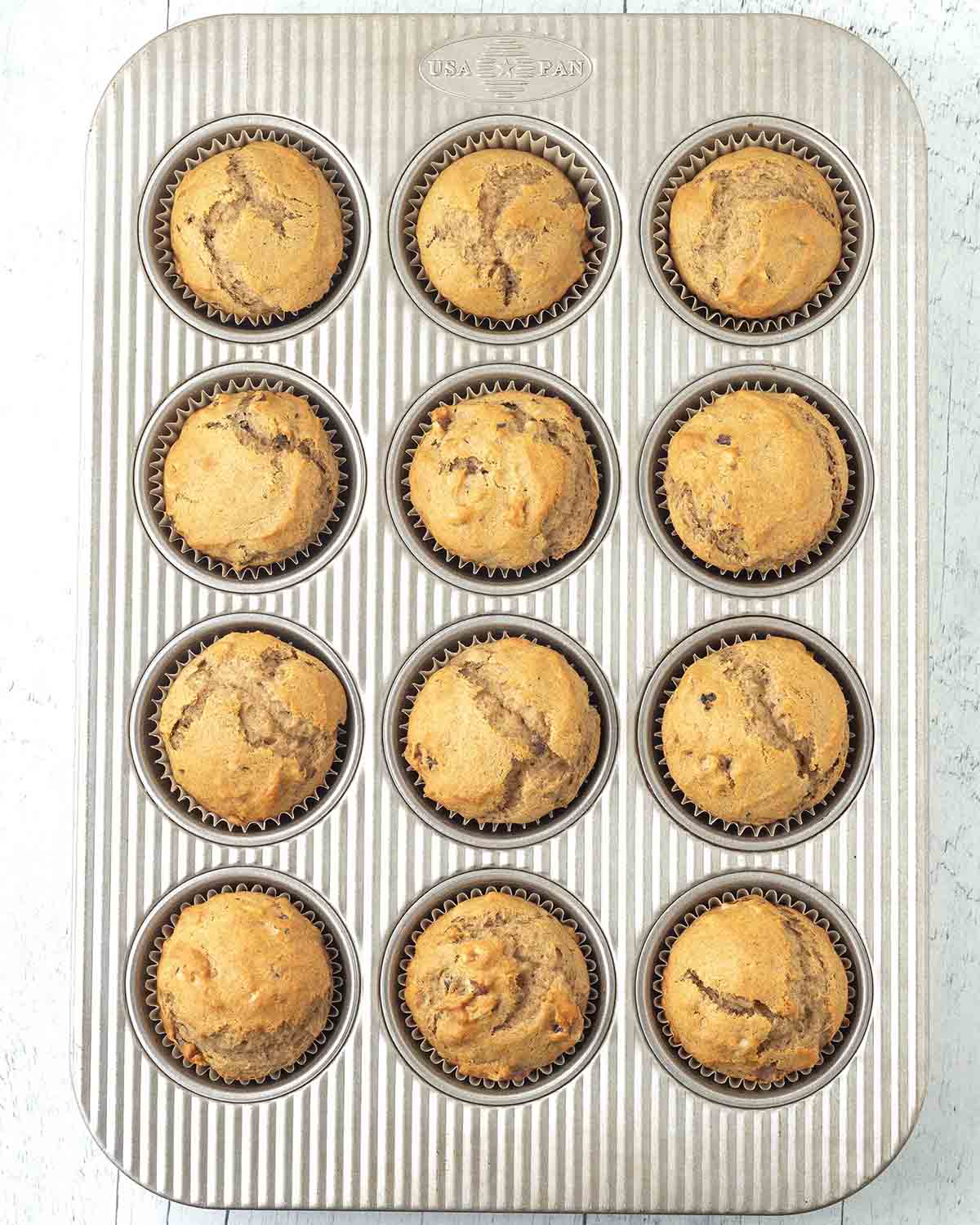 Freshly baked vegan banana muffins in a muffin pan.