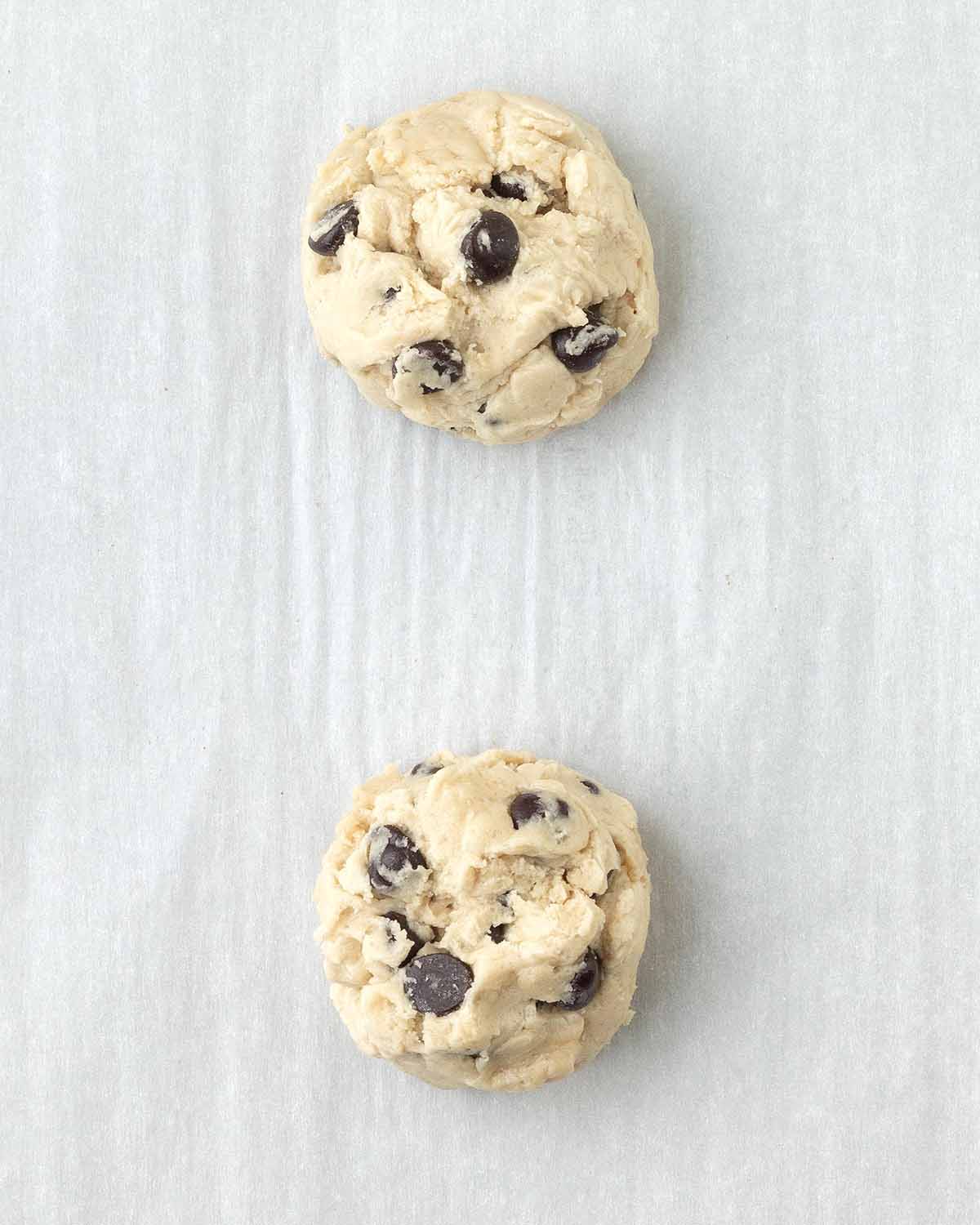 Two balls of cookie dough on a parchment lined baking sheet.
