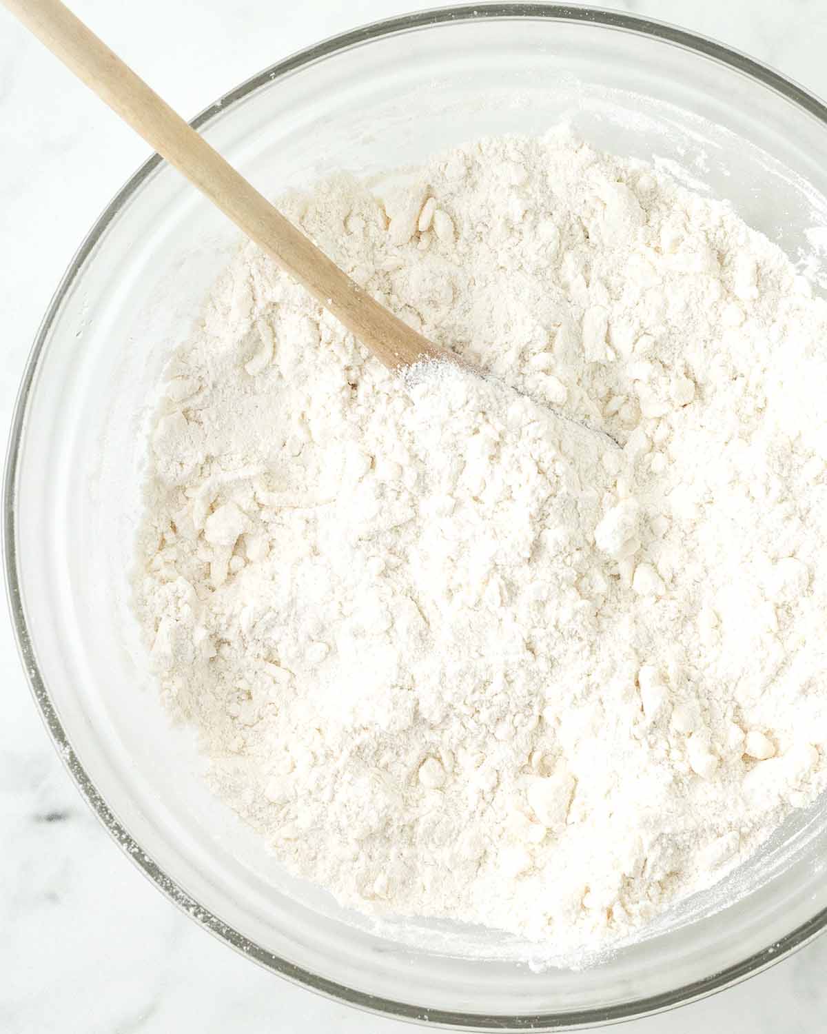 Dry ingredients and grated butter mixed together in a glass bowl.