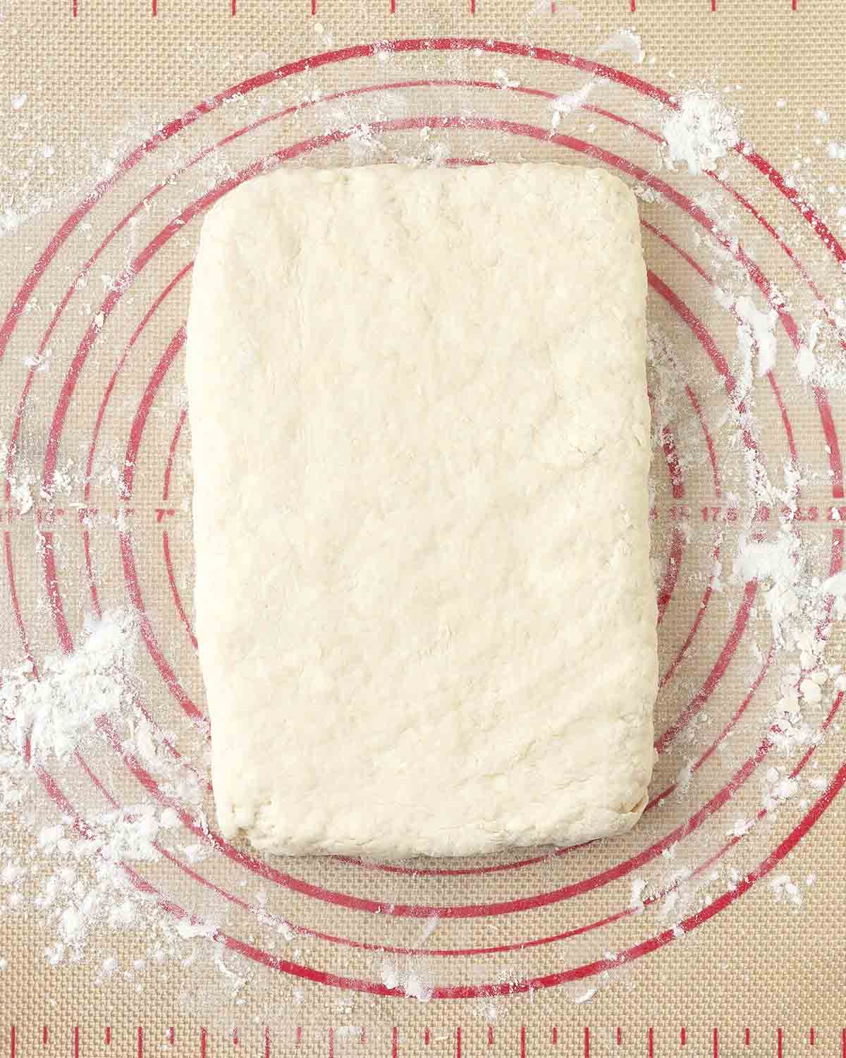 Biscuit dough shaped into a rectangle on a floured pastry mat.