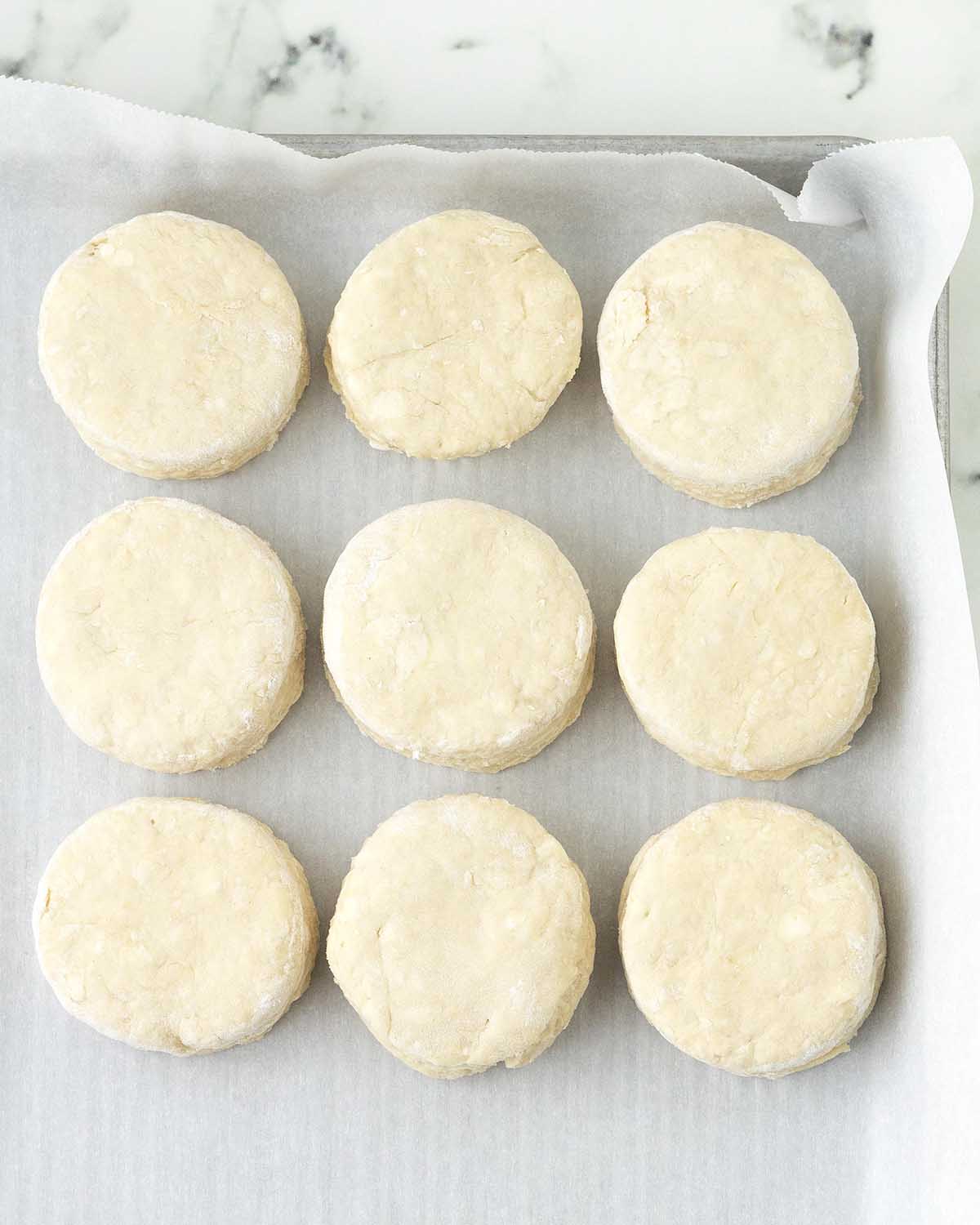 Unbaked biscuits in a parchment lined baking pan.
